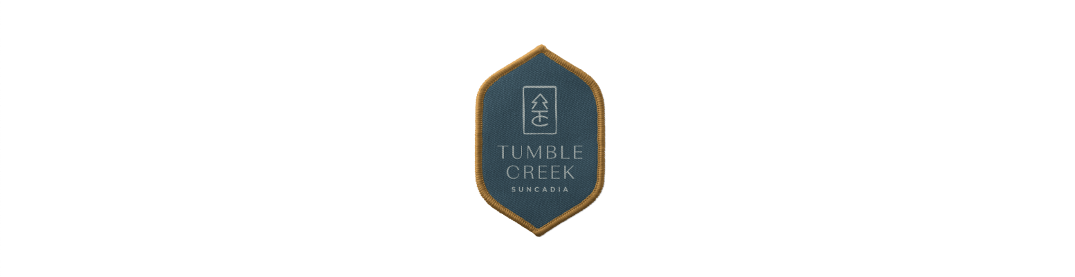 Emblem with "Tumble Creek Suncadia" text on a shield-shaped patch featuring a tree and TC logo above, capturing the essence of Suncadia Resort Washington.